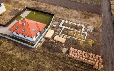 Działka rolno budowlana z gotowym domem i fundamentami pod kolejny. Materiały budowlane czekają na rozpoczęcie prac.