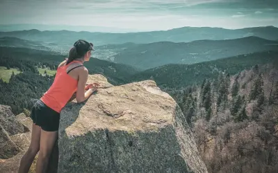 Une randonneuse admire le paysage depuis un rocher. Une parfaite destination randonnée pour s'évader.