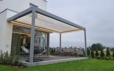 Nowoczesna pergola z oświetleniem LED. Zastanawiasz się, czym pomalować pergole? Ta szara konstrukcja świetnie komponuje się z meblami ogrodowymi i zielenią.