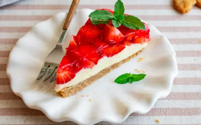Ein Stück Erdbeerkuchen mit Keksboden, garniert mit frischer Minze.