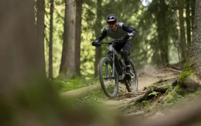 Rowerzysta w kasku i okularach zjeżdża po wyboistej leśnej ścieżce. To właśnie jest **co to enduro** – jazda po trudnym terenie.
