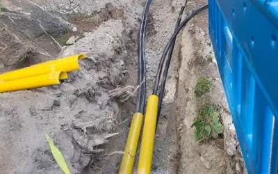 Kabel elektryczny w ziemi, chroniony żółtymi osłonami, przygotowany do zakopania zgodnie z przepisami.