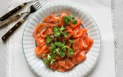 Vacker tallrik med gravad lax, garnerad med dill och gröna blad. Frågan är om man kan frysa gravad lax för att spara den till senare.