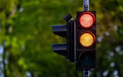 Sygnalizacja świetlna z czerwonym i żółtym światłem. Kierowca zastanawia się, czy zdąży na przejazd na żółtym świetle, czy lepiej zahamować.