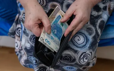 Dłonie wkładają polskie banknoty do portmonetki. Zastanawiasz się, co oznacza zawieszenie renty? To może być trudne, gdy pieniądze są potrzebne.