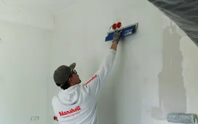Maler spachtelt Rigips-Wand glatt für ein makelloses Finish.
