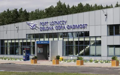 Nowoczesny budynek lotniska w Zielonej Górze-Babimoście z dużymi oknami i napisem "PORT LOTNICZY ZIELONA GÓRA-BABIMOST".