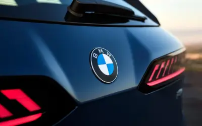 Nowe znaczki samochodowe BMW błyszczą na ciemnoniebieskim lakierze. Widoczne są charakterystyczne tylne światła.