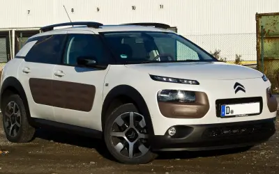 Biały Citroen Cactus z brązowymi wstawkami Airbump na drzwiach, zaparkowany na brudnym podjeździe.