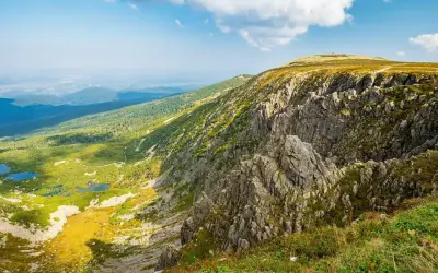 Widok na skaliste zbocze Szrenicy i malownicze Śnieżne Kotły z górskimi stawami w dole.