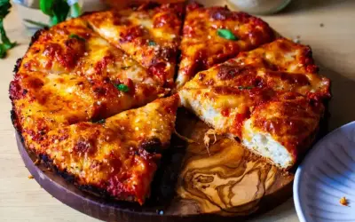 Pyszna pizza rzymska z chrupiącym ciastem, ciągnącym serem i aromatycznym sosem pomidorowym, podana na drewnianej desce.