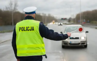 Policjant w kamizelce z napisem "POLICJA" zatrzymuje samochód. Czyżby to kolejny mandat dla tego kierowcy?