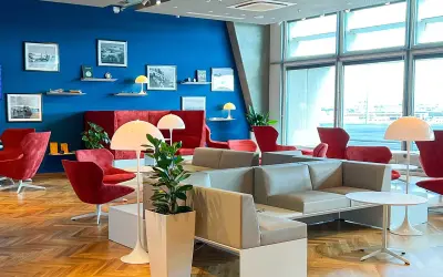 Gemütliche Lounge mit roten Sesseln und grauen Sofas, ideal für Reisende mit Priority Pass Stuttgart.