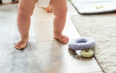 Małe stópki na ciepłej podłodze. Czy ogrzewanie podłogowe jest zdrowe dla maluchów? Miękkie dywany i zabawki zachęcają do pierwszych kroków.