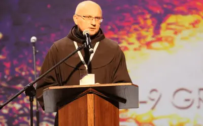 Ksiądz w habicie przemawia przy mównicy. Jego opinia kościoła jest ważna dla zgromadzonych.