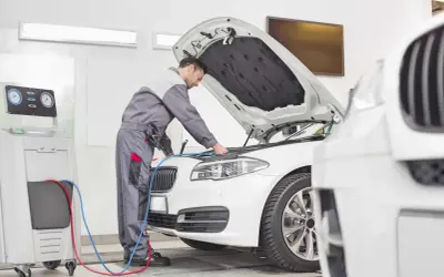 Mechanik sprawdza auto, by dowiedzieć się, ile kosztuje przegląd samochodu. Urządzenie diagnostyczne podłączone do silnika.
