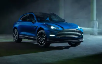 Niebieski Aston Martin DBX 707 lśni w mrocznym, industrialnym otoczeniu.