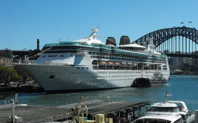 La Rhapsody of the Seas, un'imponente nave da crociera, attracca nel porto di Sydney, con l'iconico ponte sullo sfondo.