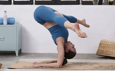 Mujer en posturas invertidas de yoga, con las piernas flexionadas. Una práctica segura y beneficiosa, incluso durante el embarazo.