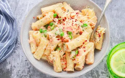 Pyszne danie z makaronem rigatoni, kawałkami łososia, groszkiem i kremowym sosem, posypane serem i płatkami chili. Idealna pasta z łososia na obiad.