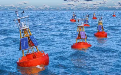 Plusieurs bouées de navigation solaires orange flottent sur une mer bleue agitée. Ces balises bateau guident les navires.