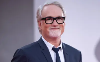 David Fincher, reżyser znany z mrocznych i wciągających filmów, w eleganckim garniturze i okularach.