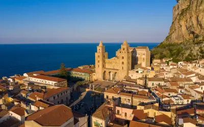 Cefalù cosa vedere: la maestosa Cattedrale Normanna domina il borgo con le sue torri, incastonata tra il mare blu e la rocca imponente.