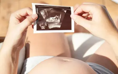 Kobieta trzyma zdjęcie USG, na którym widać zarodek. To nie lewatywa, co to jest? To obraz życia.