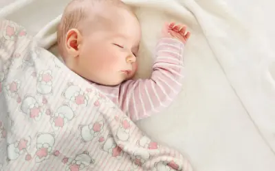 Śpiące dziecko otulone kocykiem w misie. Idealne wymiary kocyka dla niemowlaka zapewnią komfortowy sen.