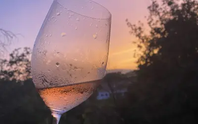 Calice di vino rosato, con gocce di condensa, al tramonto. Un brindisi alla vinificazione in rosato.