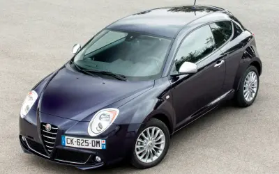 Elegancki, granatowy Alfa Romeo MiTo na tle asfaltu. Wiele osób szuka alfa romeo mito opinie, by poznać ten model.