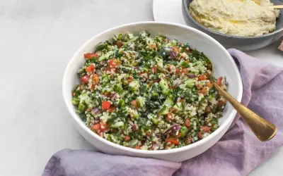 Kolorowa sałatka tabbouleh z komosą ryżową, pomidorami, ogórkiem i ziołami. Idealna alternatywa dla tradycyjnej wersji.