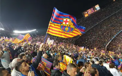 Tłum kibiców na stadionie unosi flagę FC Barcelona, symbol Katalonii.