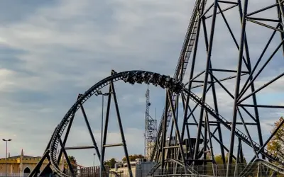 Pasażerowie na wagonikach pędzą po torach najszybszego rollercoastera w Europie, który wznosi się ku niebu.