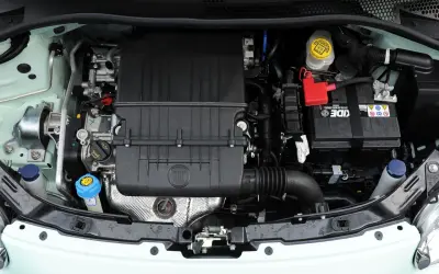 Silnik Fiata 500 L z widocznym logo FIAT na czarnej obudowie. Widać akumulator, płyny i elementy układu chłodzenia.