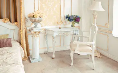 Camera da letto in stile provenzale francese, con letto, tavolino, sedia e decorazioni dorate.