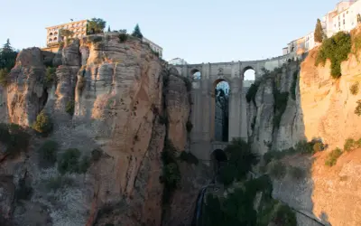 Impresionante puente de piedra sobre un profundo tajo, ideal para rutas por Ronda. Edificios se asoman al abismo.