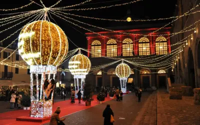 Luci scintillanti e palloni luminosi creano un'atmosfera magica per un week end a Rimini. Persone passeggiano su un tappeto rosso, ammirando le decorazioni natalizie.