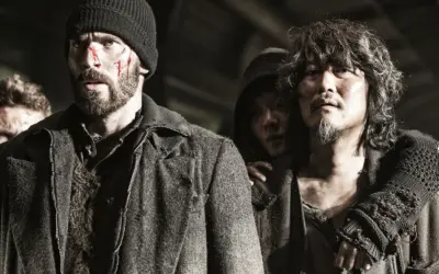 Zraniona obsada Snowpiercer: Arka przyszłości, w tym Chris Evans, w surowych, postapokaliptycznych strojach.