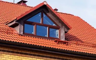 Ein Dachfenster mit dreieckigem Oberlicht und roten Ziegeln. Informieren Sie sich, was kostet eine gaube für Ihr Haus.