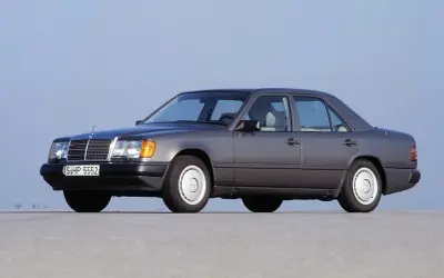 Szary Mercedes W124, symbol najbardziej niezawodnych samochodów, stoi na płaskiej nawierzchni.