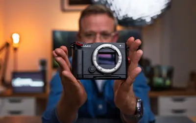 Mężczyzna trzyma aparat Lumix, gotowy do uchwycenia każdej chwili. To jego pelna klatka marzeń.