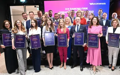 Grupa osób w eleganckich strojach pozuje z dyplomami na tle sceny z logo "Rzeczpospolita".