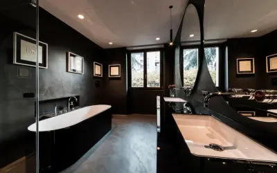 Elegantes, dunkles Badezimmer mit freistehender schwarzer Wanne, Doppelwaschbecken und moderner Spiegelarchitektur.