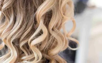 Piękne, falowane włosy z subtelnym balejażem blond, dodającym im blasku i głębi.