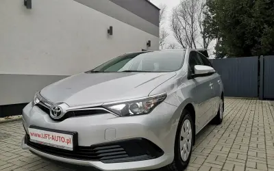 Srebrna Toyota Auris 1.6 benzyna zaparkowana na podjeździe z kostki brukowej.