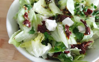 Chrupiąca surówka z sałaty lodowej z serem feta, suszonymi pomidorami i pestkami dyni.