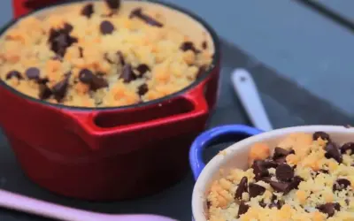 Deux ramequins de crumble pomme banane chocolat, l'un rouge, l'autre bleu, garnis de pépites de chocolat.