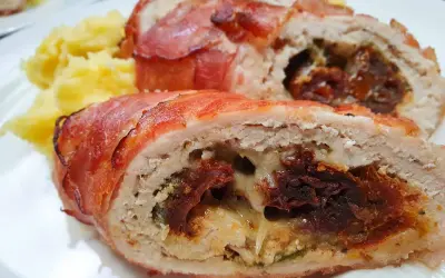 Soczysta pierś z kurczaka zawijana w boczku z serem, nadziewana suszonymi pomidorami i ziołami, podana z puree ziemniaczanym.
