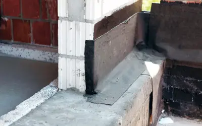 Papa na fundament chroni przed wilgocią, widoczna na narożniku budowy.